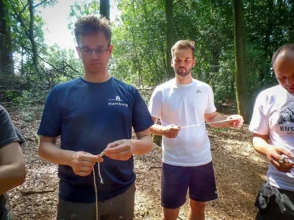 Teilnehmer knoten Seile im Wald, um Techniken zu üben