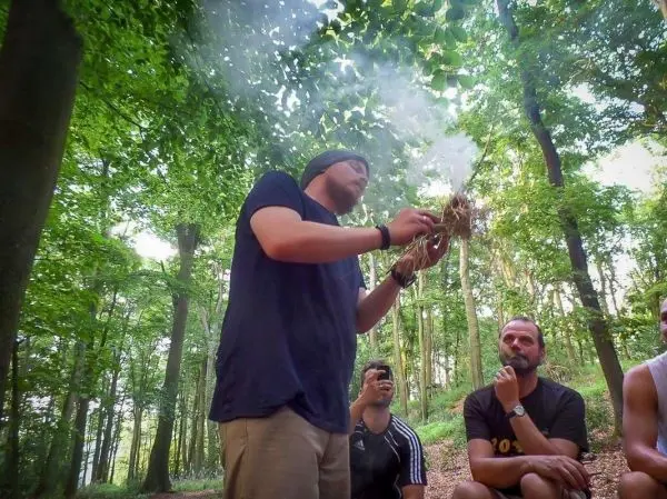 Zunder glimmt in den Händen eines Mannes im Wald