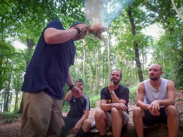 Zunder glimmt in der Hand, während Zuschauer aufmerksam beobachten
