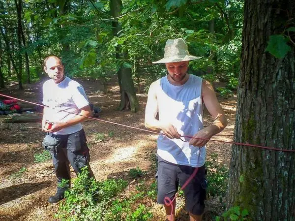 Zwei Personen arbeiten an einer Seilquerung zwischen Bäumen im Wald