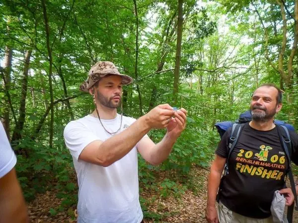 Zwei Personen im Wald, einer hält ein kleines Objekt in der Hand