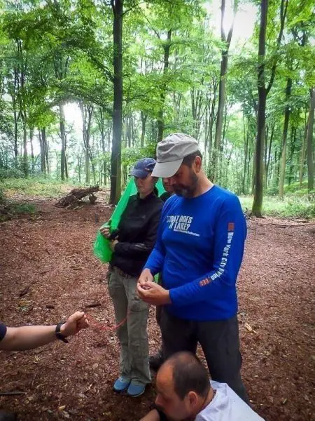 Zwei Personen stehen im Wald und arbeiten mit einem Seil