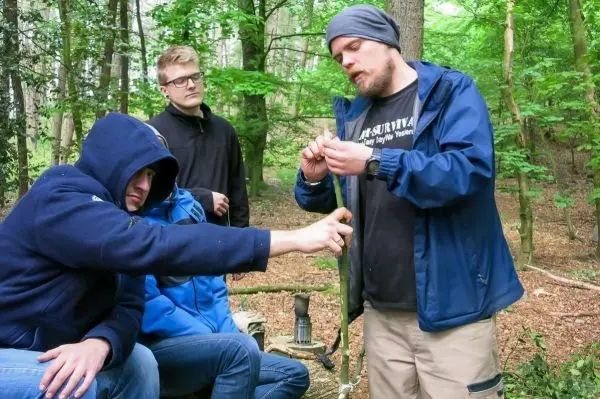 Ein Mann demonstriert eine Technik mit einem Seil, während drei Personen aufmerksam zuschauen