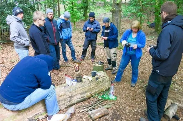 Gruppe bereitet Mahlzeit am improvisierten Kochplatz im Wald