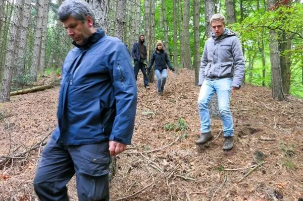 Gruppe bewegt sich durch einen bewaldeten Hang mit Laub und Tannennadeln