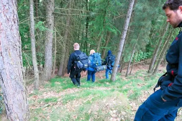 Gruppe trägt eine improvisierte Trage durch den Wald