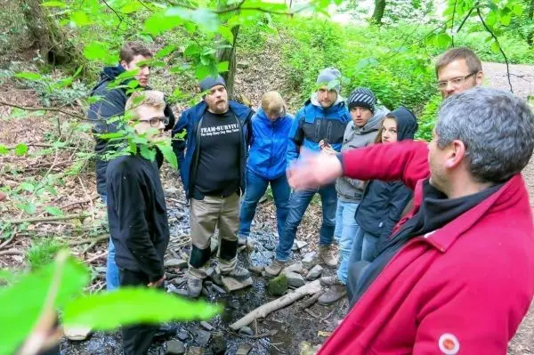 Gruppe von Personen hört einem Redner im Wald zu