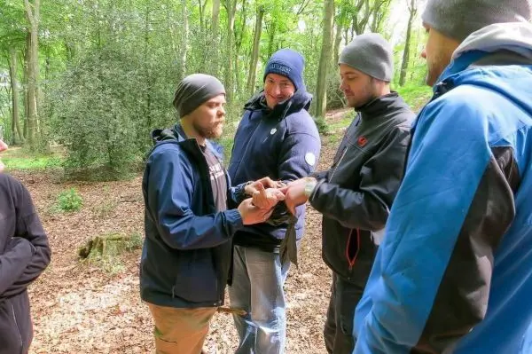 Gruppendiskussion über eine Technik im Wald, mehrere Personen um einen Teilnehmer versammelt