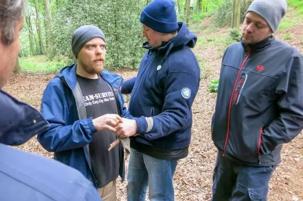Mann erhält Erste-Hilfe-Anleitung zur Bandagierung einer Verletzung im Wald