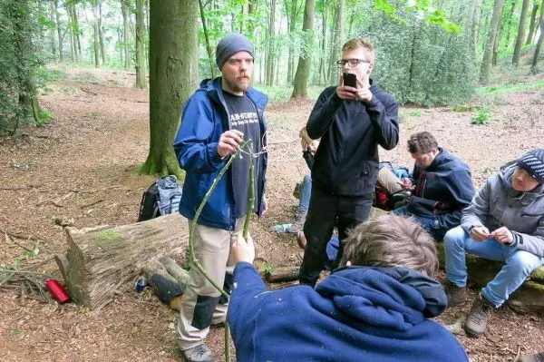 Mann hält einen Stock, während andere Teilnehmer um ihn herum stehen