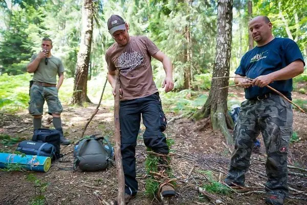 Drei Personen arbeiten im Wald mit Ästen und Ausrüstung