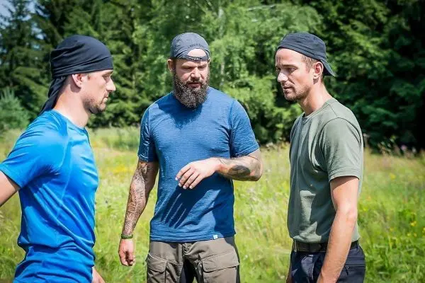 Drei Personen in Outdoor-Bekleidung diskutieren in einer Wiese