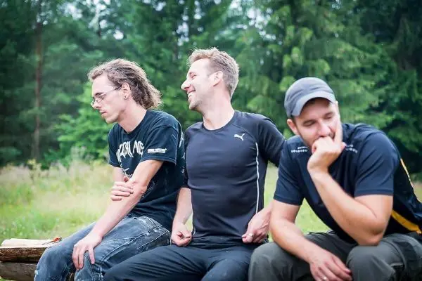 Drei Personen sitzen auf einem Baumstamm und unterhalten sich