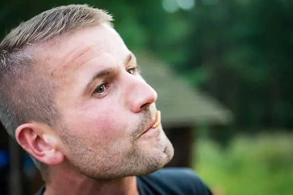 Ein Mann hält einen kleinen Gegenstand zwischen den Lippen