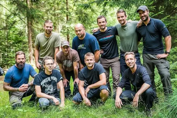 Gruppe von zehn Personen posiert im Wald auf einer Wiese