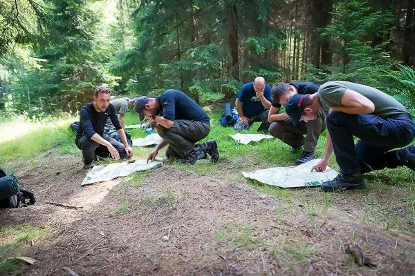 Gruppenteilnehmer analysieren Karten im Wald auf dem Boden