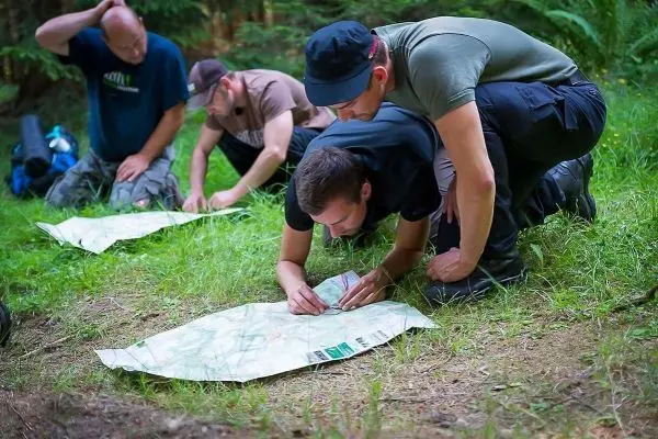 Gruppierung betrachtet eine Karte auf dem Boden im Wald