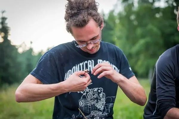 Mann bearbeitet einen Stock mit einem Messer in der Natur