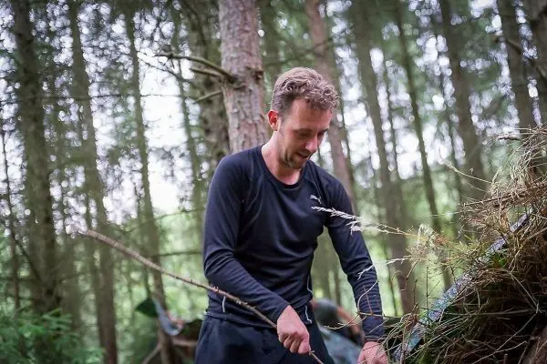 Mann bearbeitet Holzstück im Wald mit einem Messer