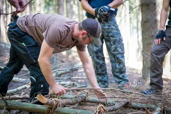 Mann bindet Äste zu einer Konstruktion im Wald