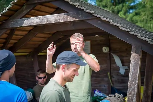 Mann erklärt etwas unter einem Holzunterstand, während andere zuhören