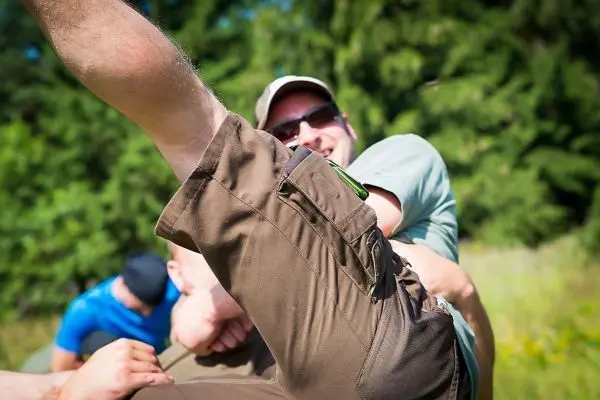 Mann hebt Bein während einer Gruppenaktivität im Freien