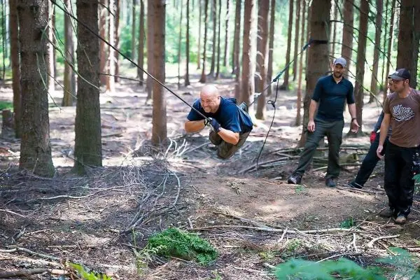 Mann überquert selbstgebaute Seilbrücke zwischen Bäumen im Wald
