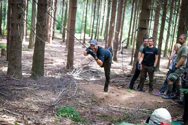 Mann überquert selbstgebaute Seilbrücke zwischen Bäumen im Wald