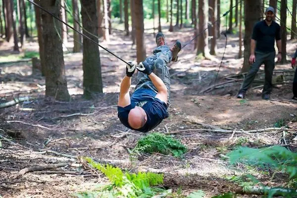 Mann überquert selbstgebaute Seilbrücke zwischen Bäumen im Wald
