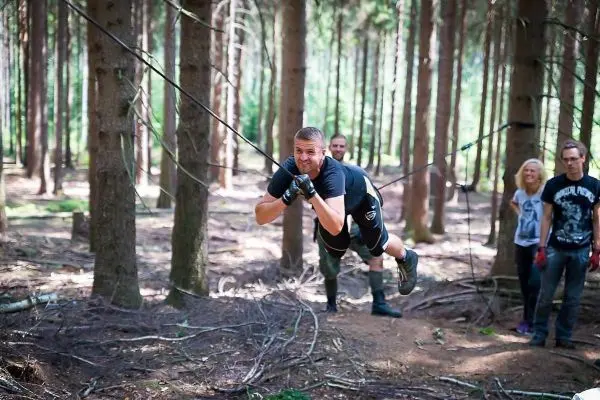 Mann überquert selbstgebaute Seilbrücke zwischen Bäumen im Wald