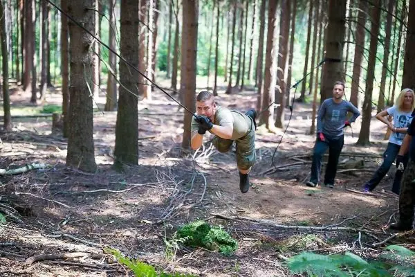 Mann überquert selbstgebaute Seilbrücke zwischen Bäumen im Wald