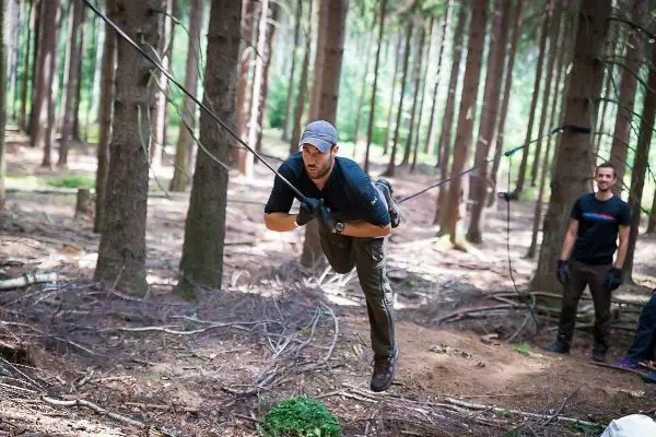 Mann überquert selbstgebaute Seilbrücke zwischen Bäumen im Wald