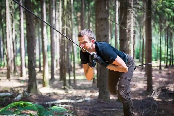 Mann zieht an einem Seil in einem Waldgebiet