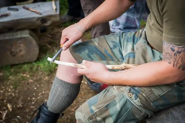 Messer bearbeitet Holzstück auf einer Sitzgelegenheit im Freien