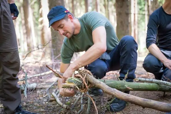 Person bindet Äste zusammen im Wald beim Überlebenstraining