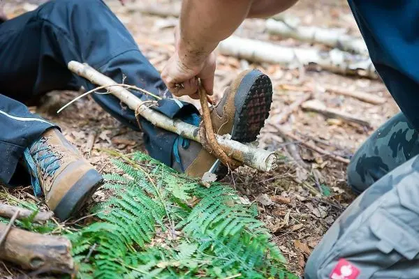 Person fixiert Stock an Bein im Wald