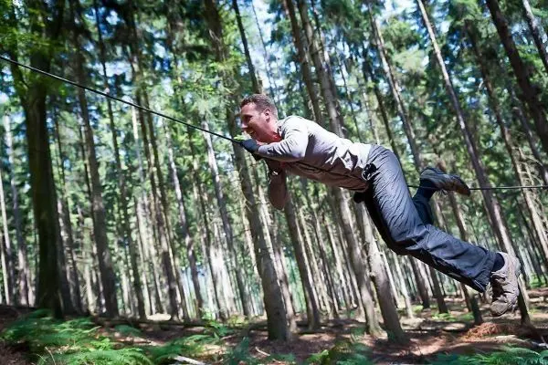 Person schwingt an einem Seil durch den Wald beim Überlebenstraining