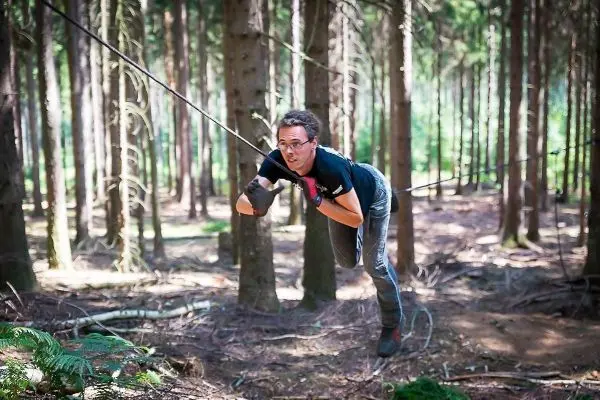 Person schwingt an Seil zwischen Bäumen im Wald