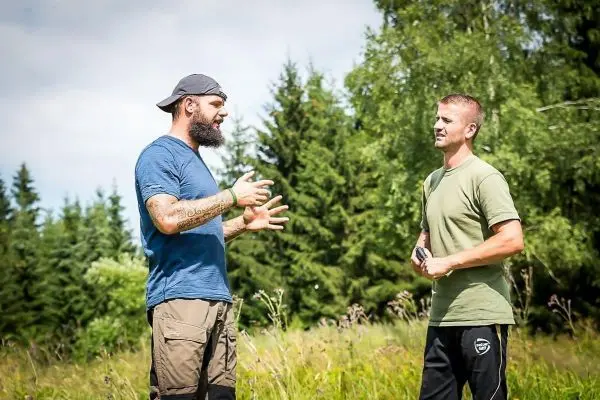 Zwei Männer stehen in einer Wiese und diskutieren miteinander