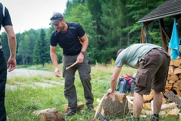 Zwei Personen bearbeiten Holz mit einem Messer und einer Axt in der Natur