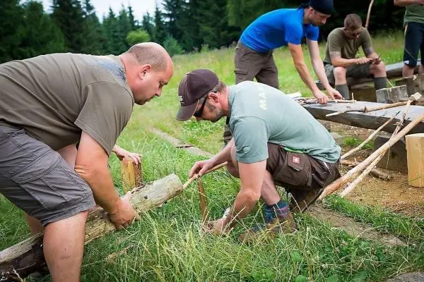 Zwei Personen bearbeiten Holzstücke zur Konstruktion einer selbstgebauten Struktur