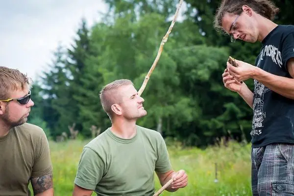 Zwei Personen beobachten einen Mann, der einen Stock in der Hand hält