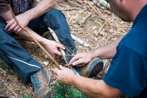 Zwei Personen binden Äste zusammen, um eine Konstruktion zu erstellen