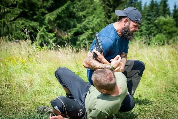 Zwei Personen im Ringen, eine hält eine Pistole in der Hand