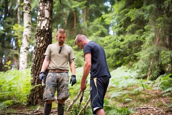 Zwei Personen sammeln Äste im Wald für eine Konstruktion