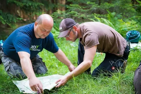 Zwei Personen studieren eine Karte auf dem Boden im Wald