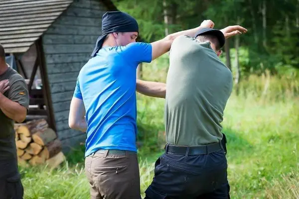 Zwei Personen üben eine Selbstverteidigungstechnik im Freien aus
