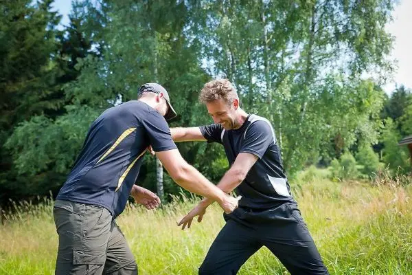 Zwei Personen üben eine Selbstverteidigungstechnik im Freien aus