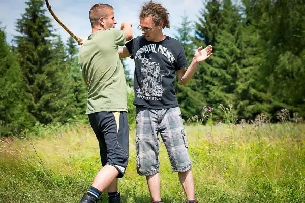 Zwei Personen üben eine Selbstverteidigungstechnik mit einem Stock im Freien