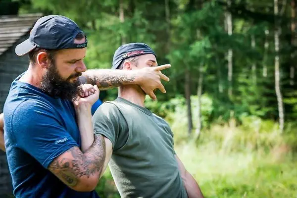 Zwei Personen üben eine Technik zur Selbstverteidigung im Freien